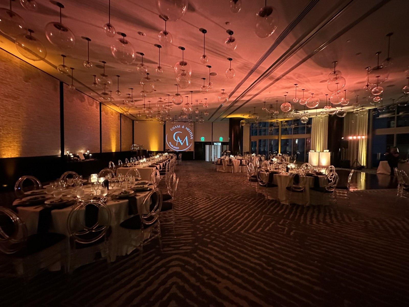 An elegant ballroom with amber uplighting by REmixed Events