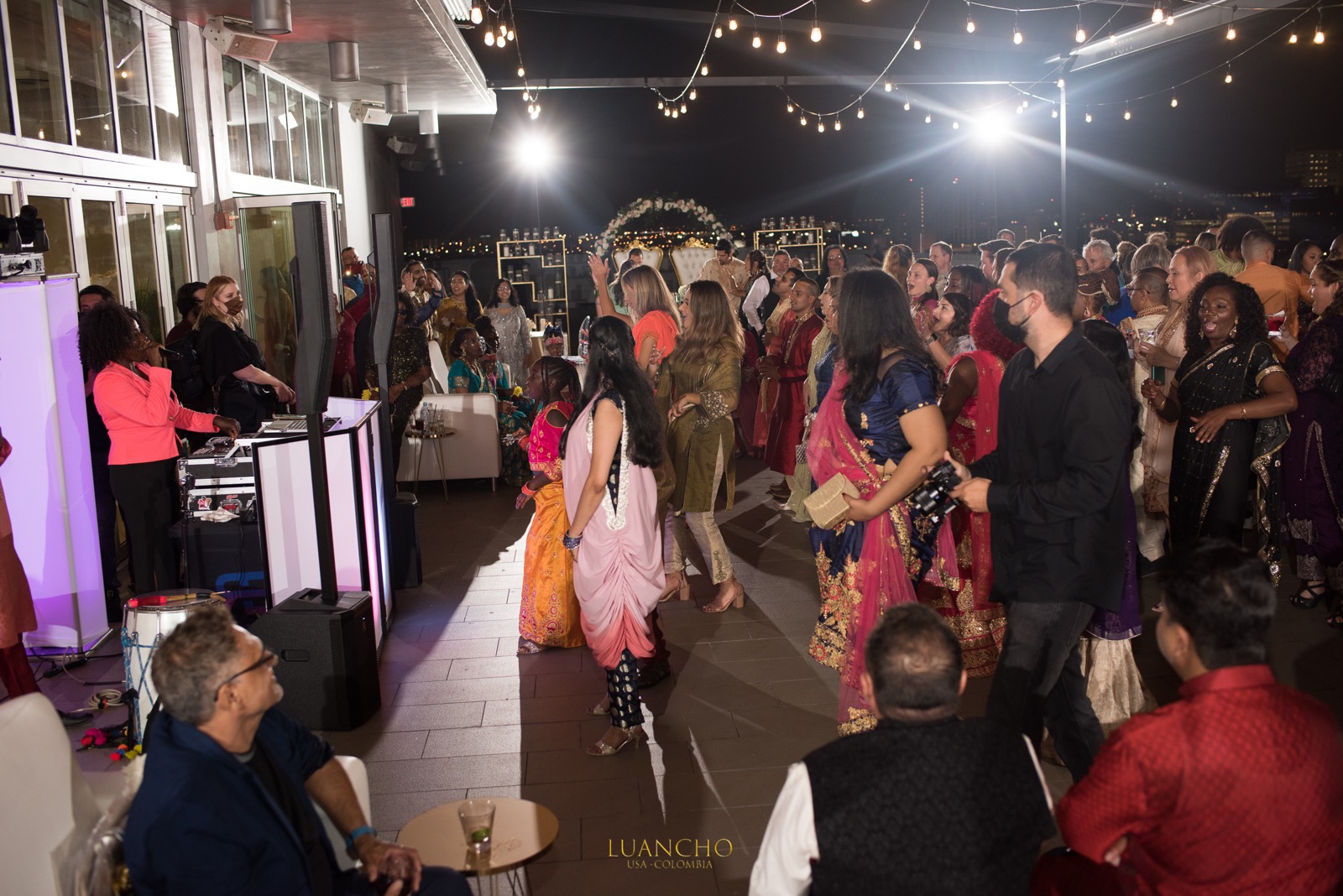 A packed wedding reception dance floor under string lights